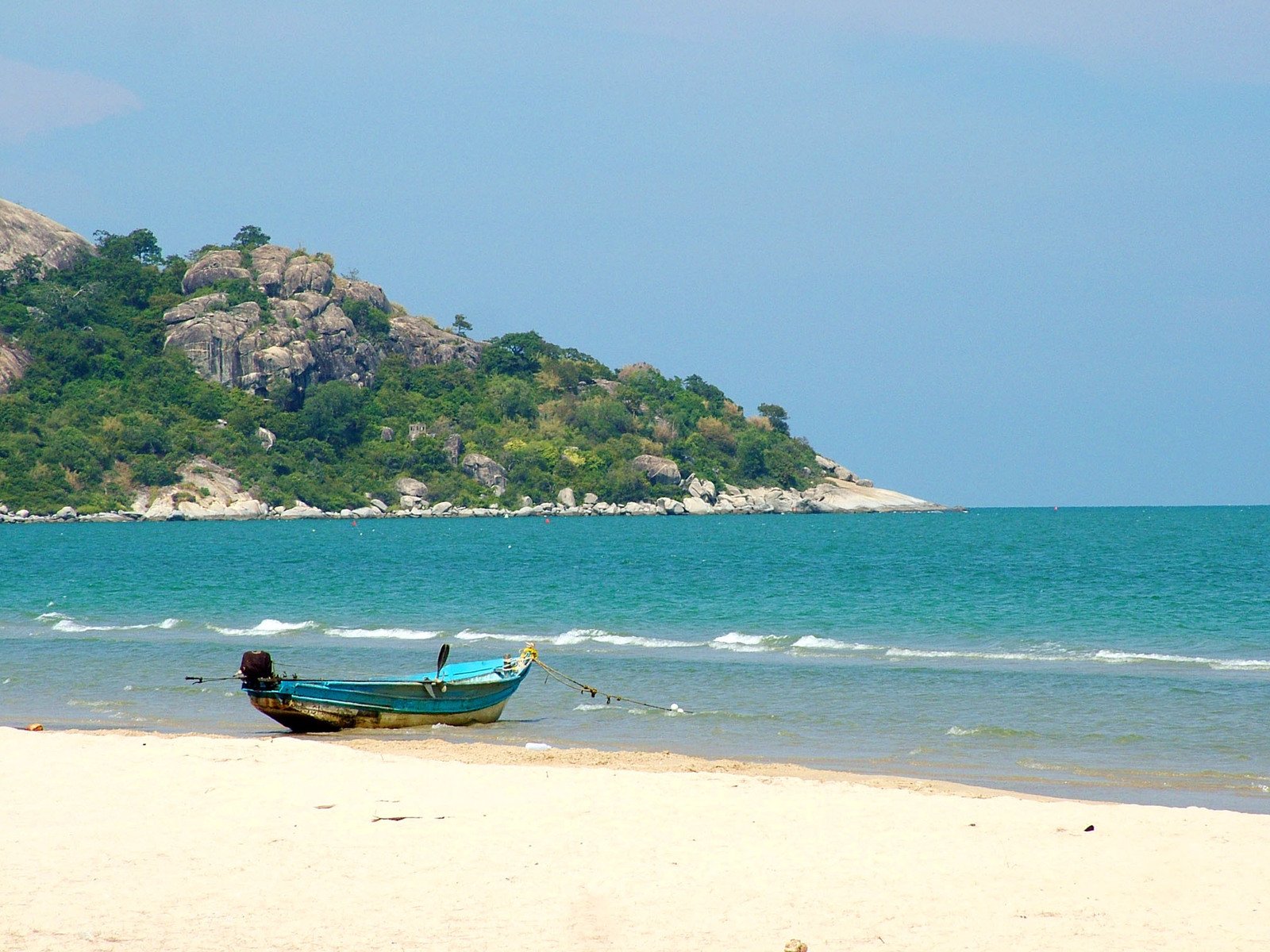 a boat sitting on top of a beach near the ocean