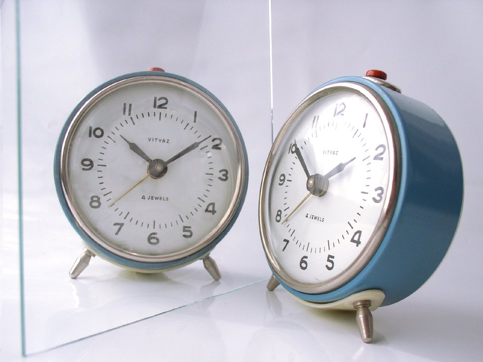 two blue clocks sitting on top of a white floor