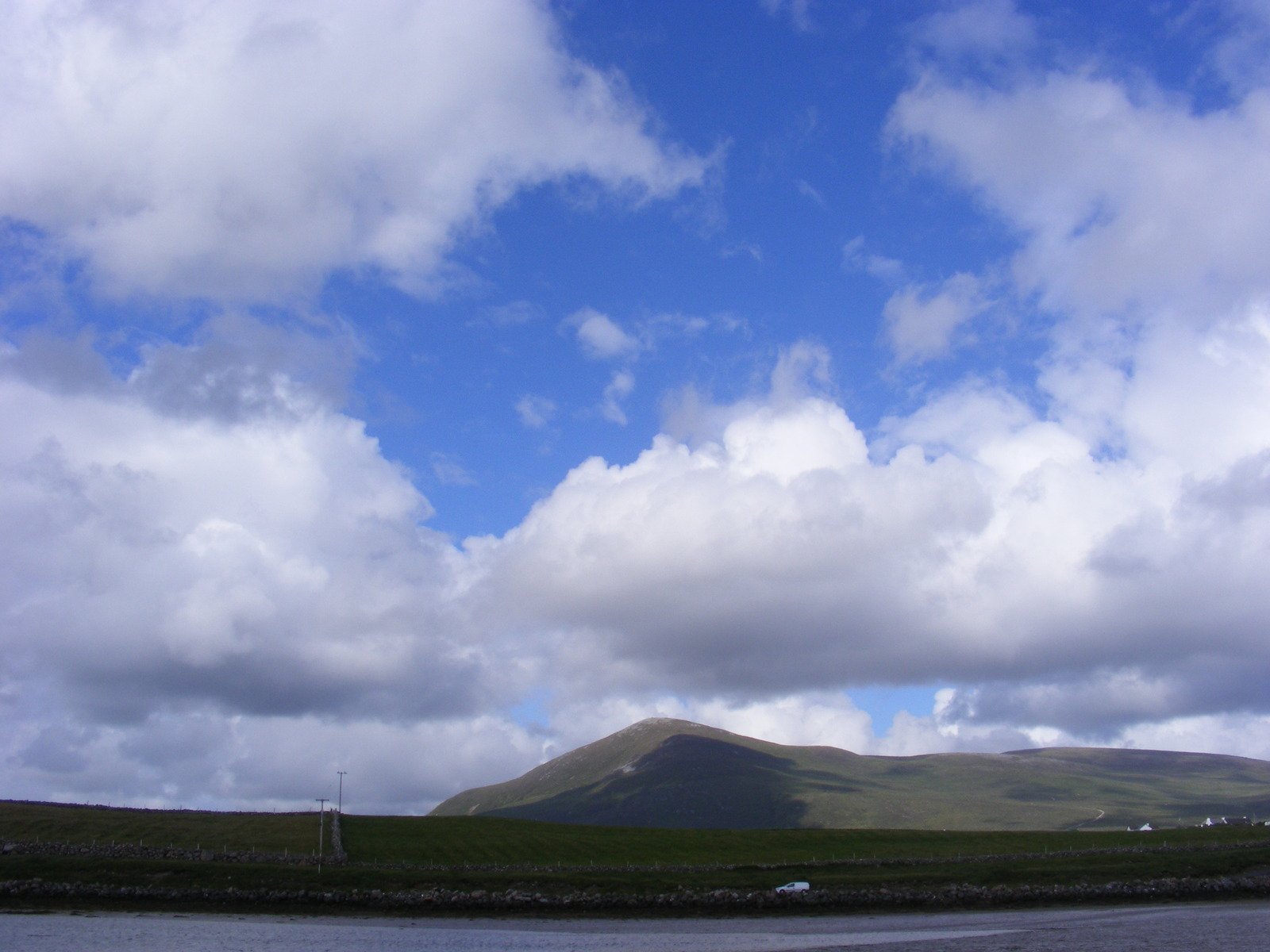 the view of some green hills, with clouds in the sky