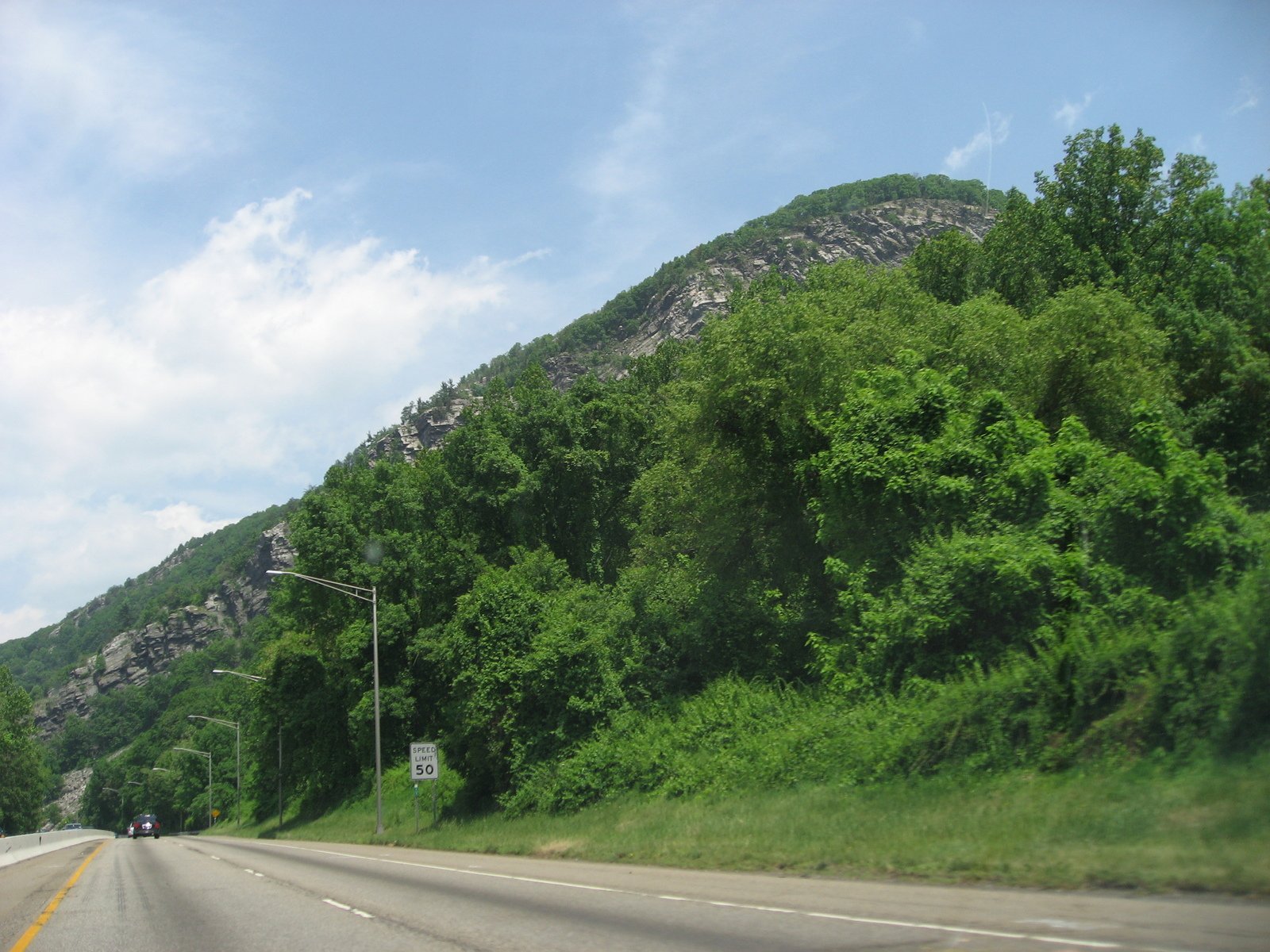 road with mountain and traffic sign during the day