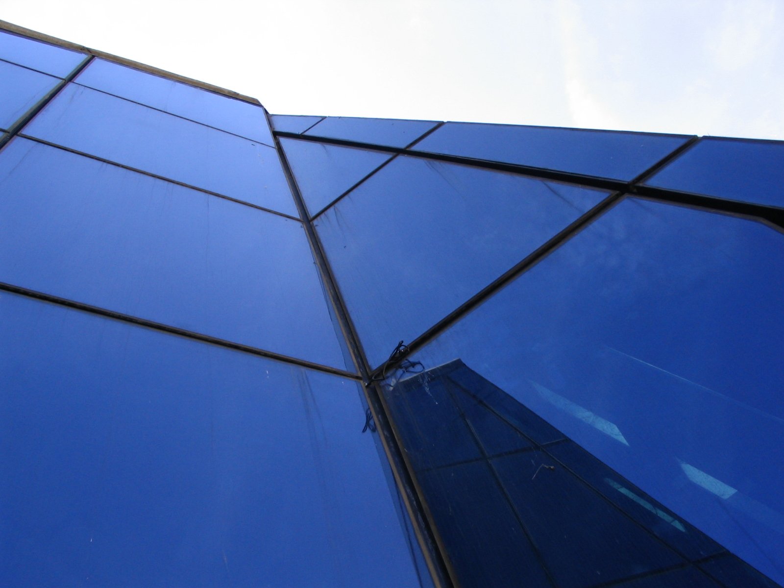 the corner of an glass building has a clear blue sky