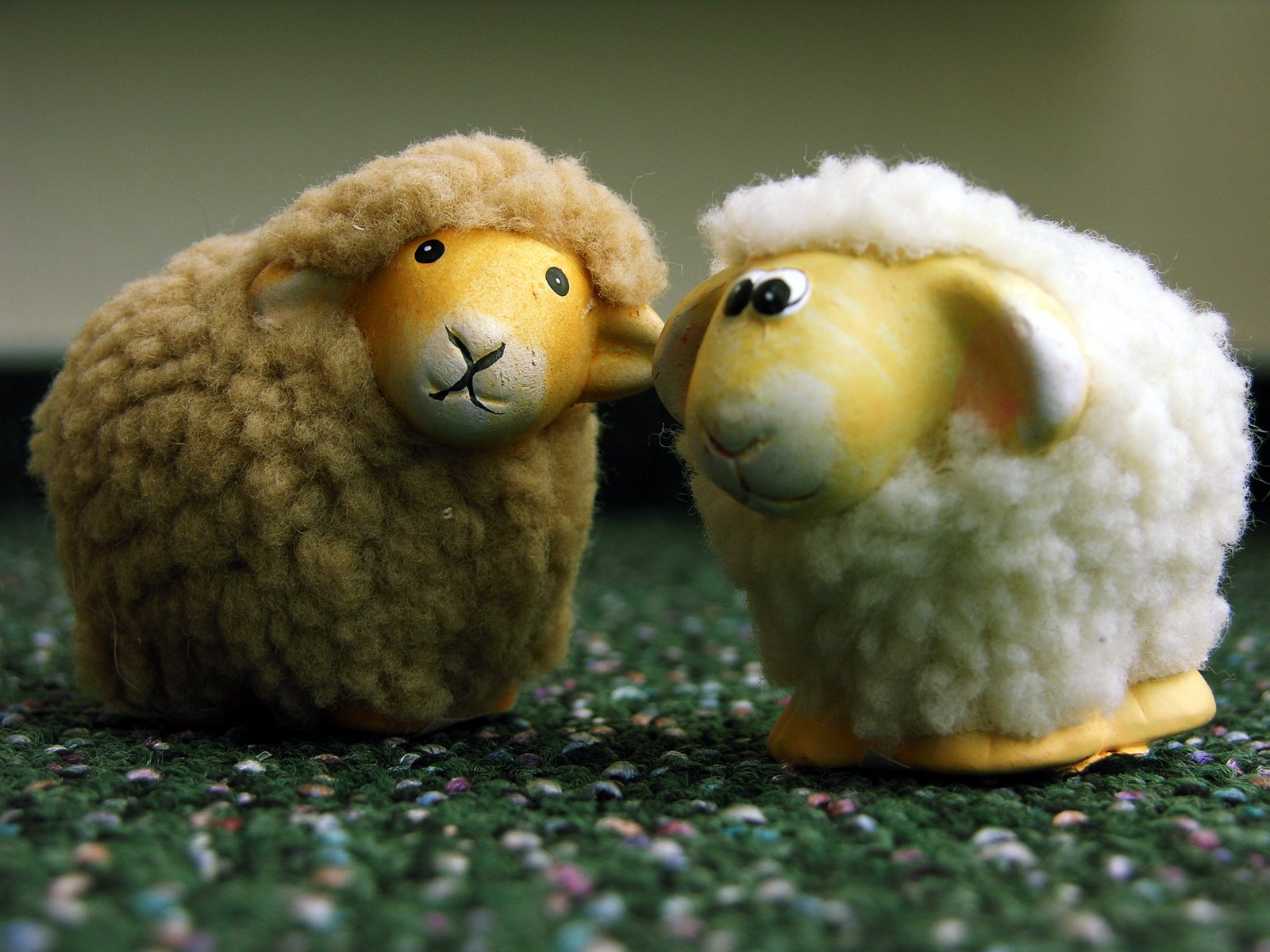 two toy sheep are standing next to each other on a rug