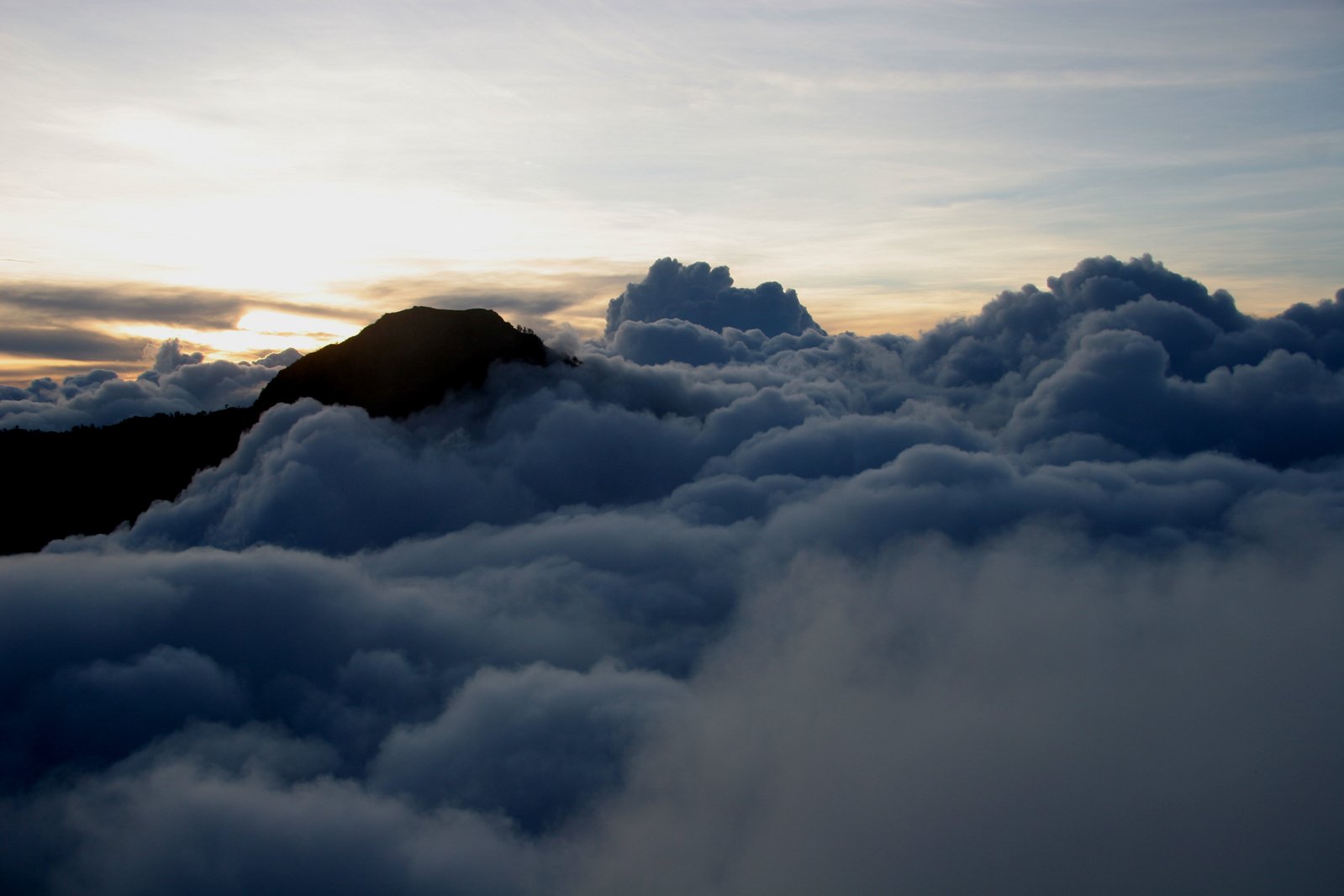 some large white clouds and some mountains at sunset