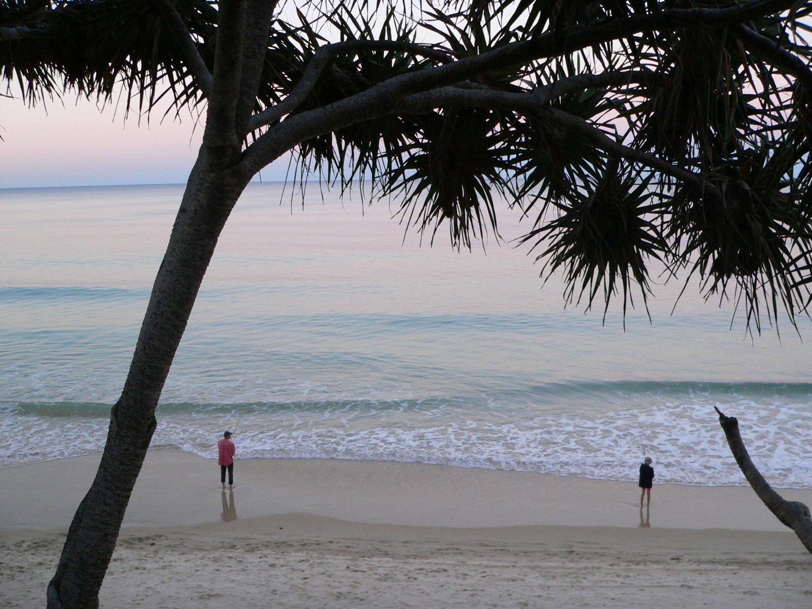 two people are standing on the beach with the ocean in the background