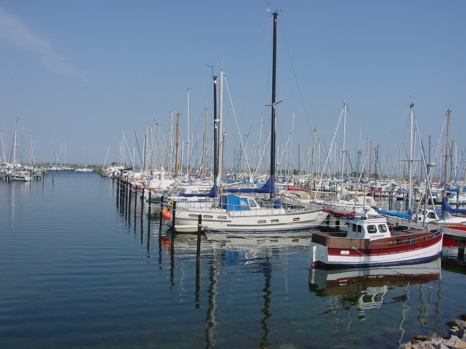 the boats are lined up in the water by the dock