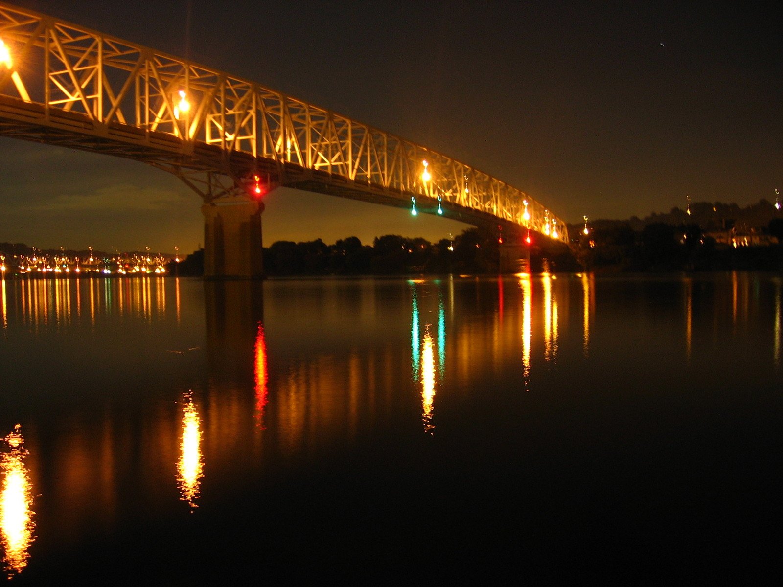 the lights of an illuminated bridge shine brightly as night approaches