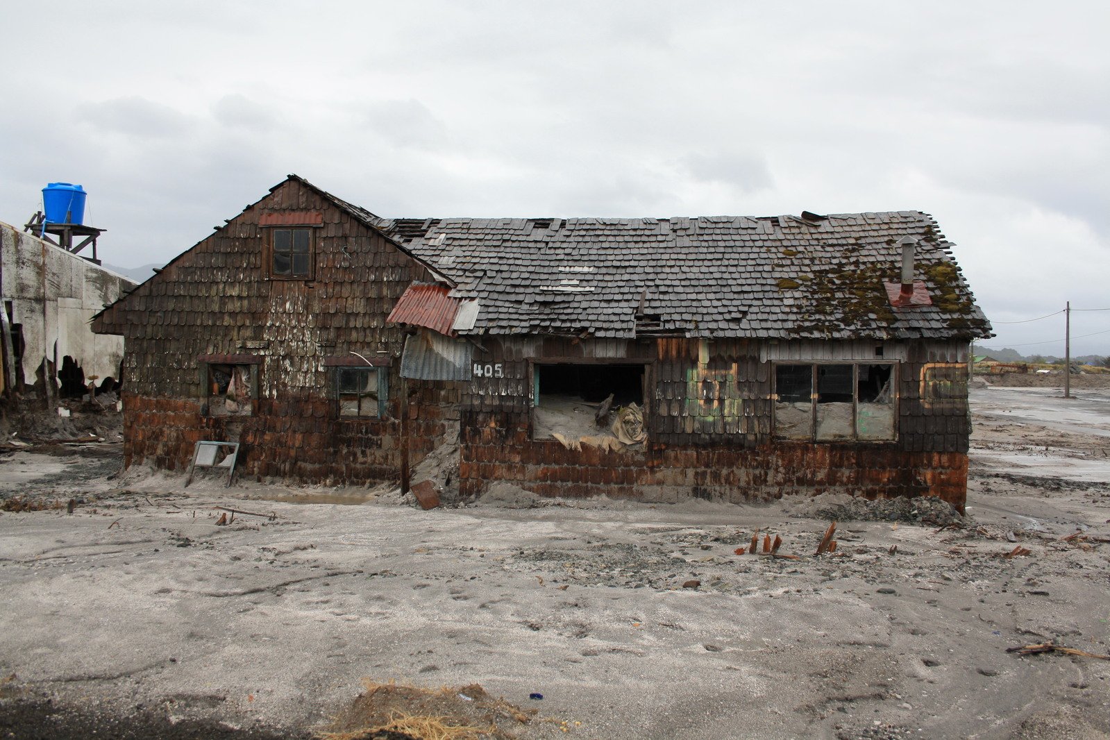 an abandoned building has boarded up windows and shingles