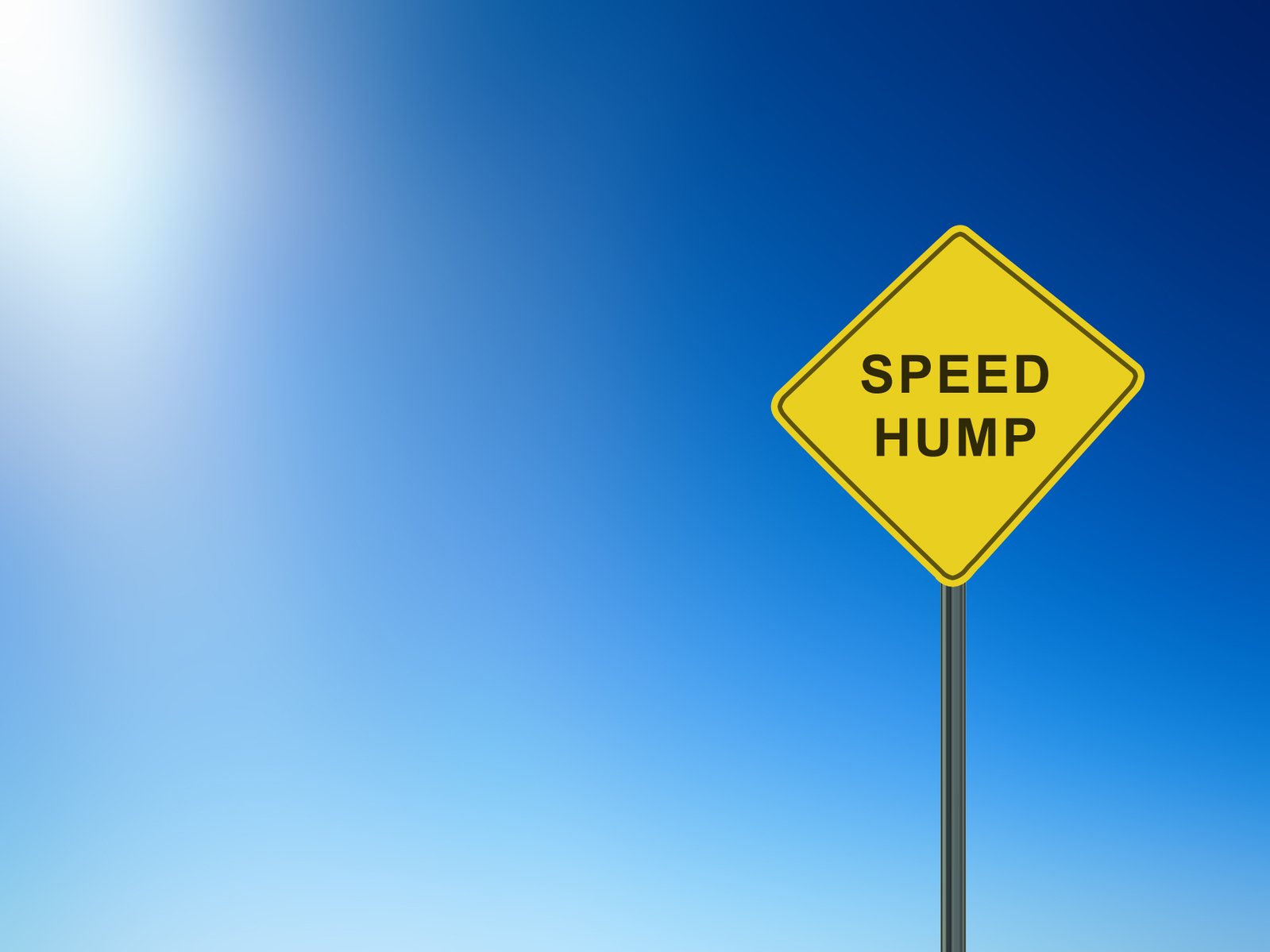 a yellow speed hump road sign against a blue sky