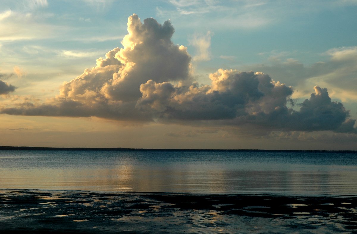 a boat in a calm body of water on a cloudy day