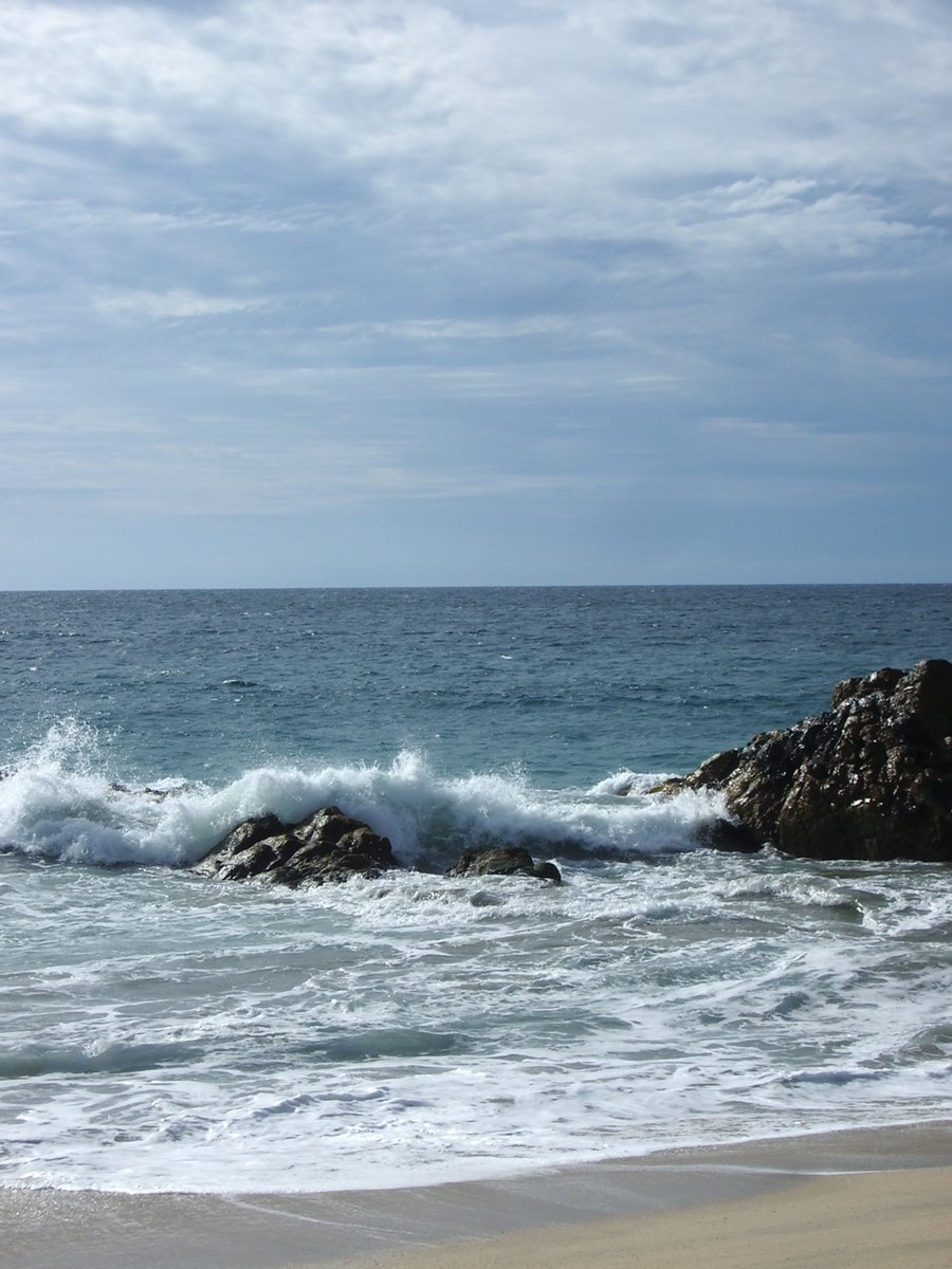 there are waves coming in from the ocean near rocks