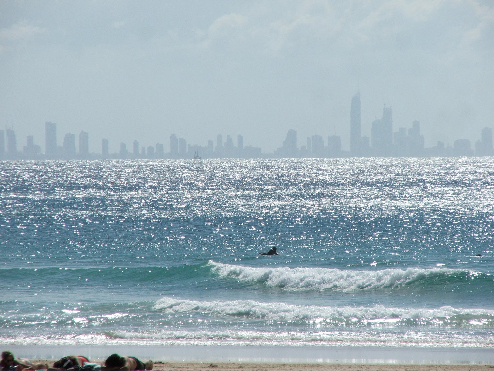surfer on the ocean and a city skyline in background
