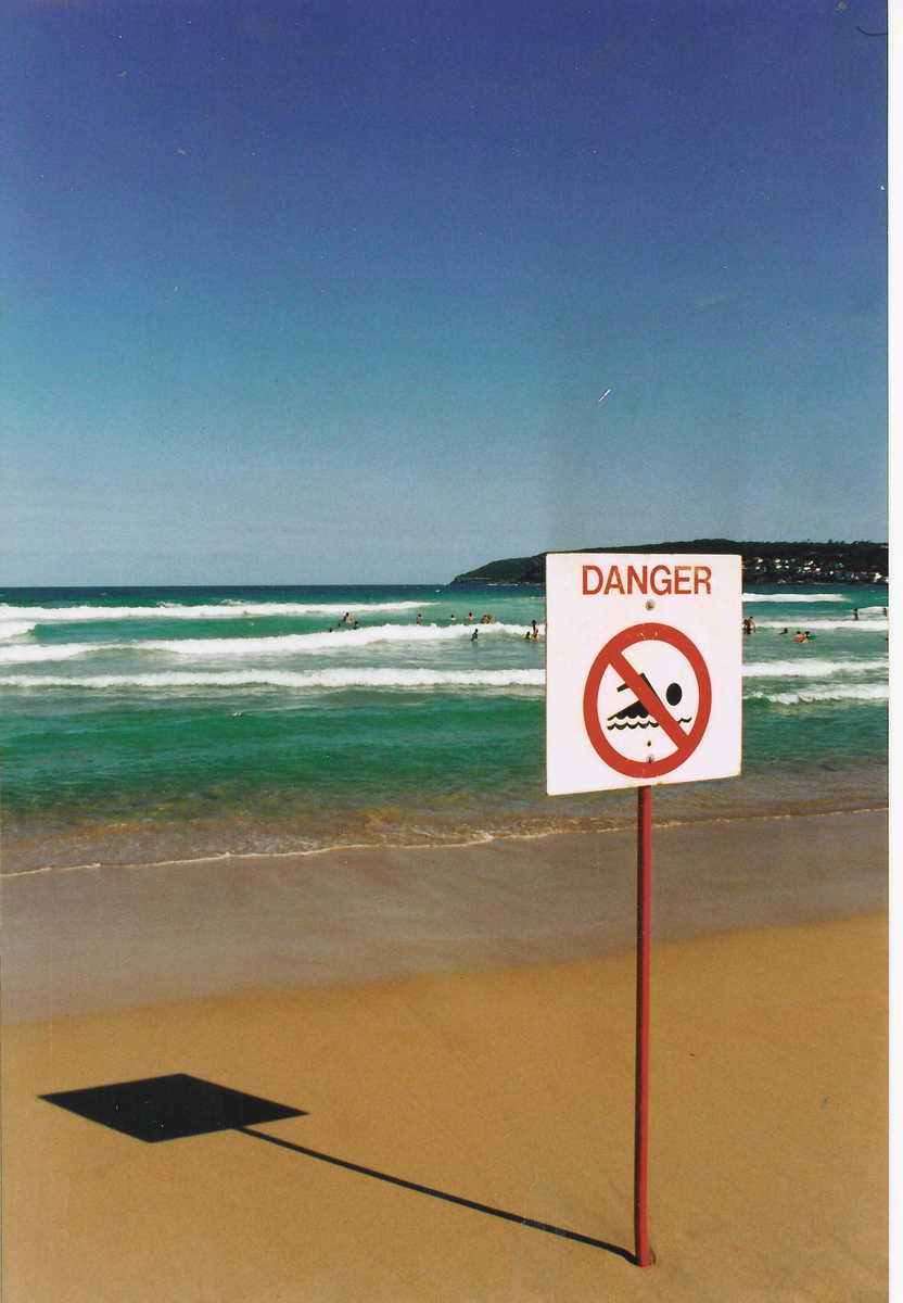 a sign warns people not to swim in the water on the beach