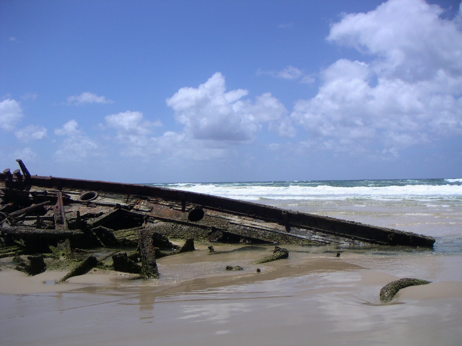 a rusted old wooden boat is lying in the sand