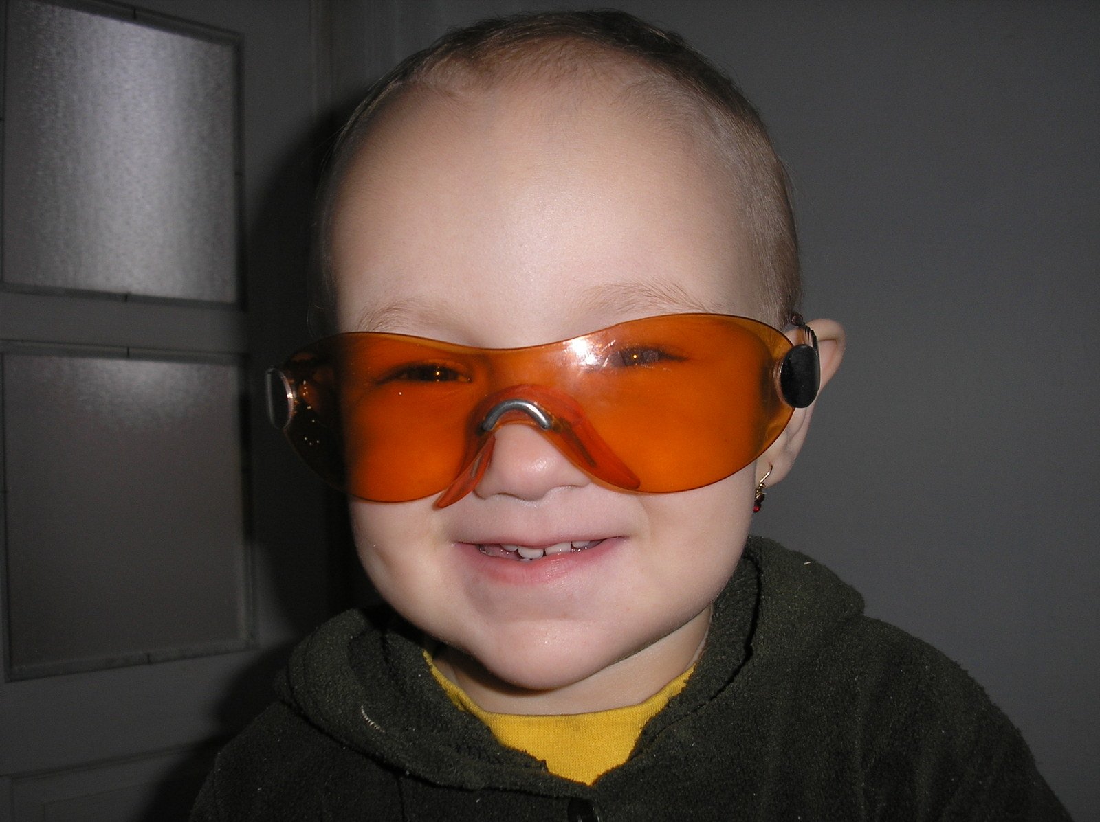 a bald headed boy wearing an orange safety glasses