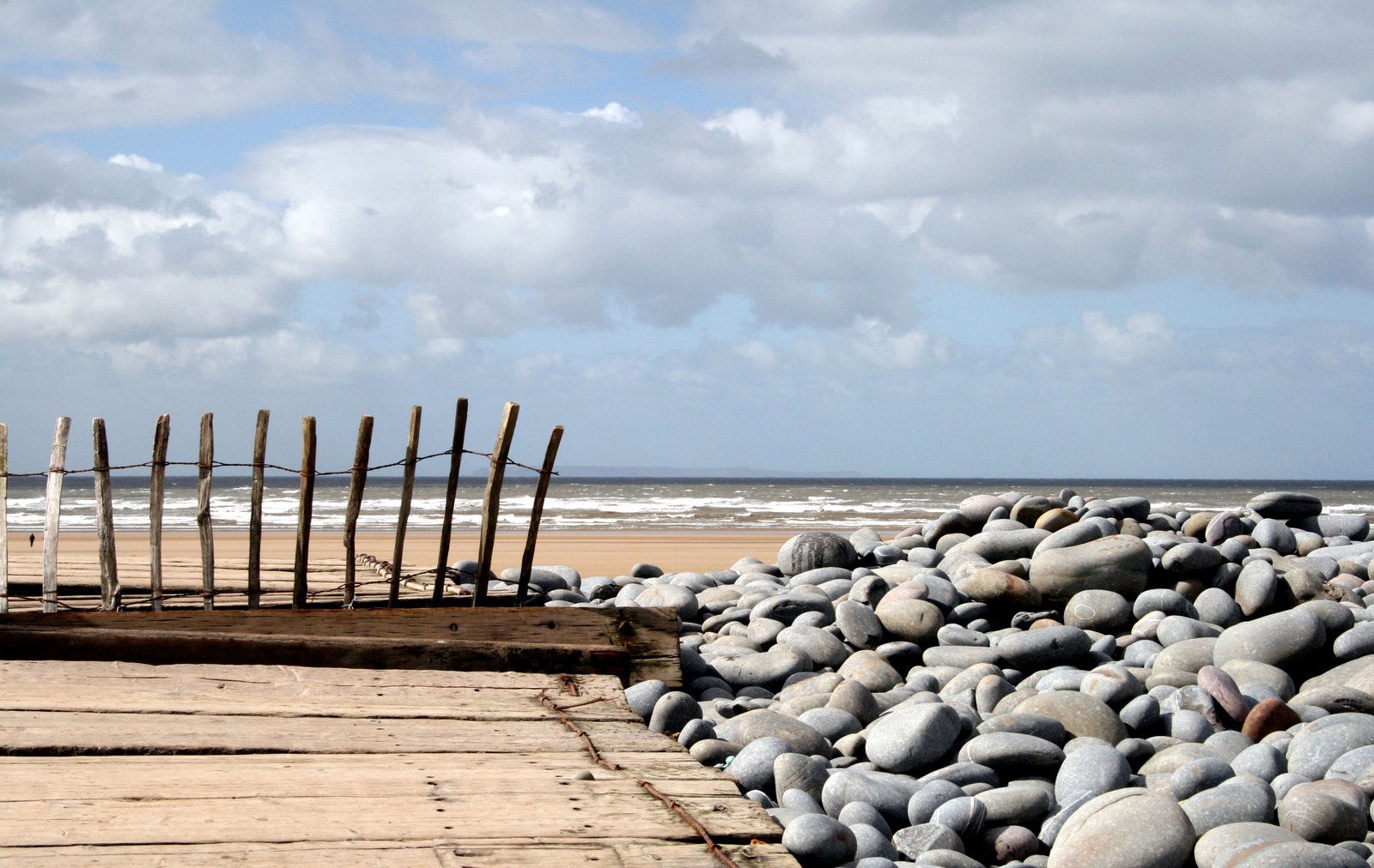 a wooden fence sitting next to a pile of rocks