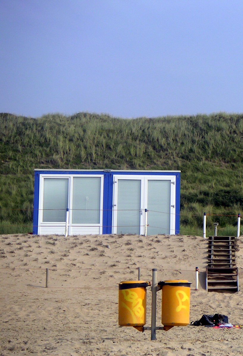 a beach with sand on the ground and two blue huts next to the water