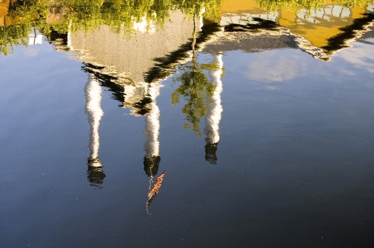 reflection of buildings in water with sky and trees