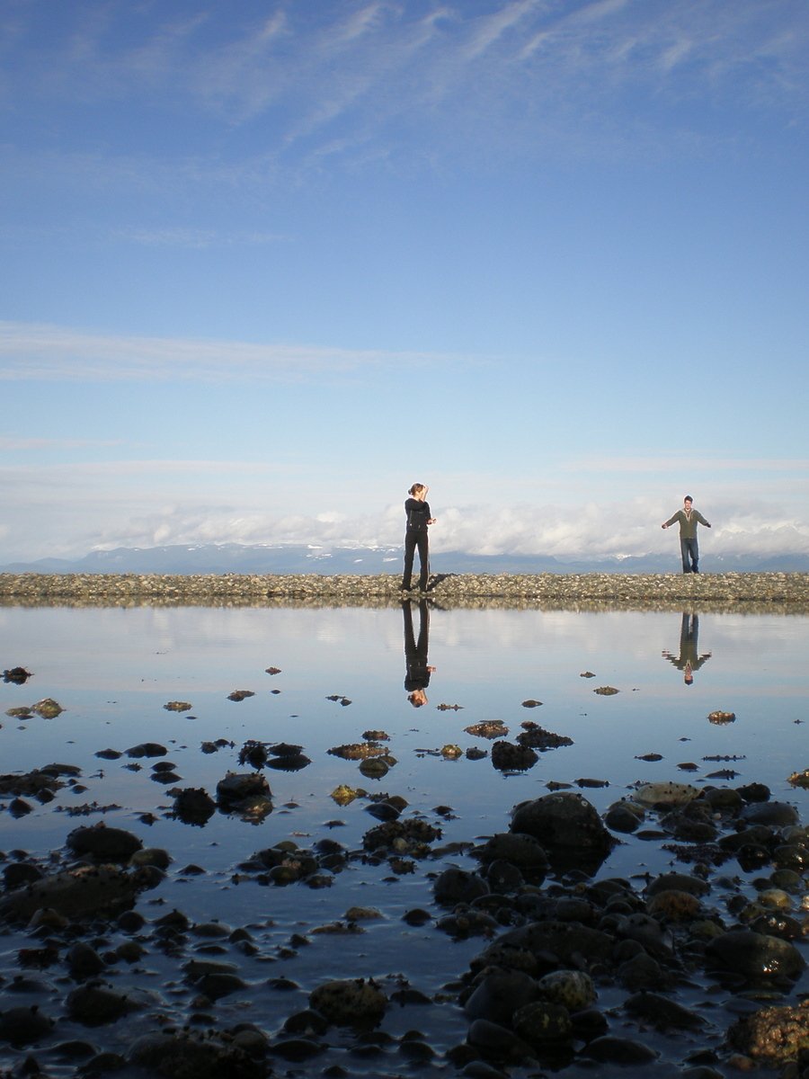 two men standing on rocks looking at the water