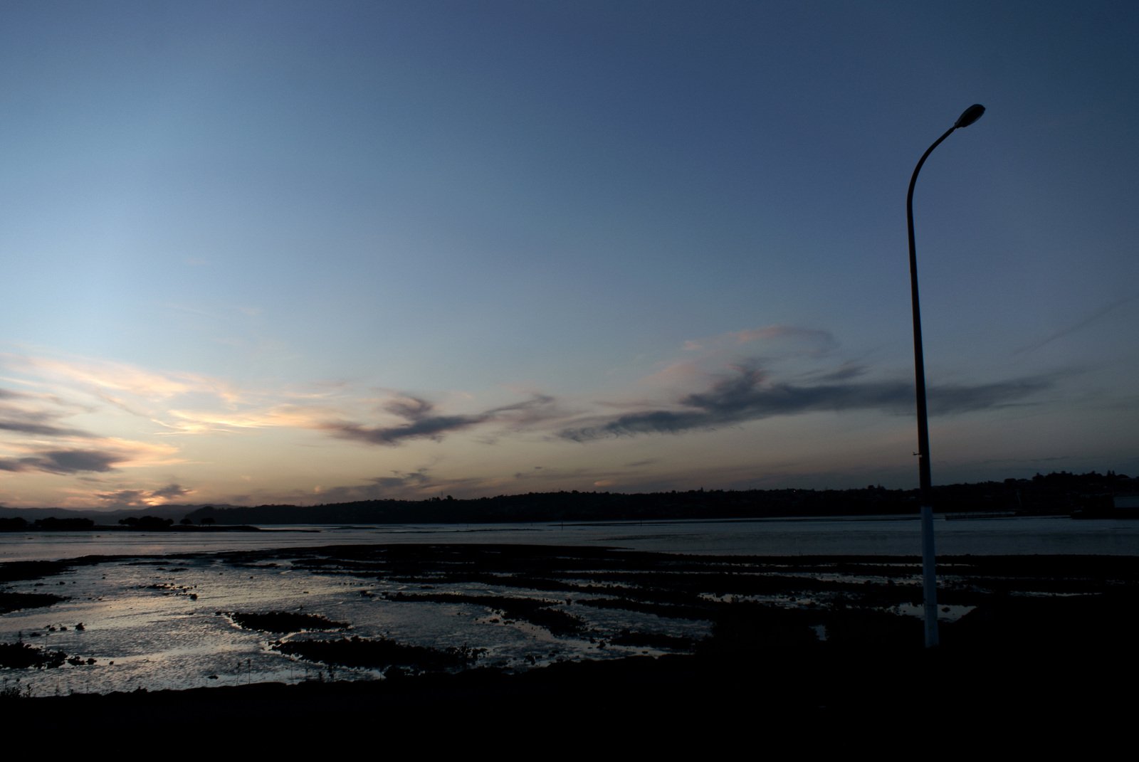 sunset and clouds reflected on a flooded beach