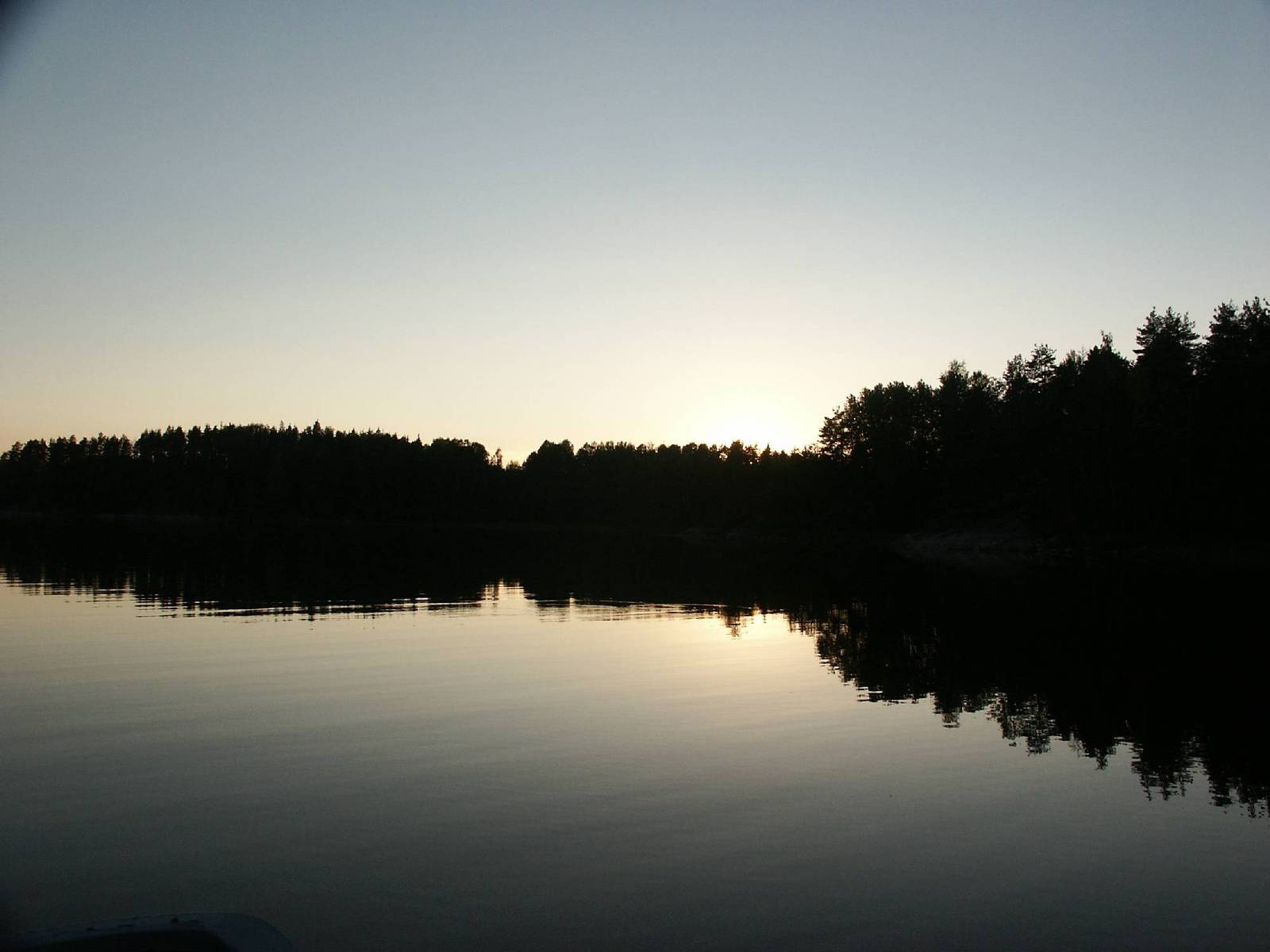 the sun rising over a lake surrounded by trees