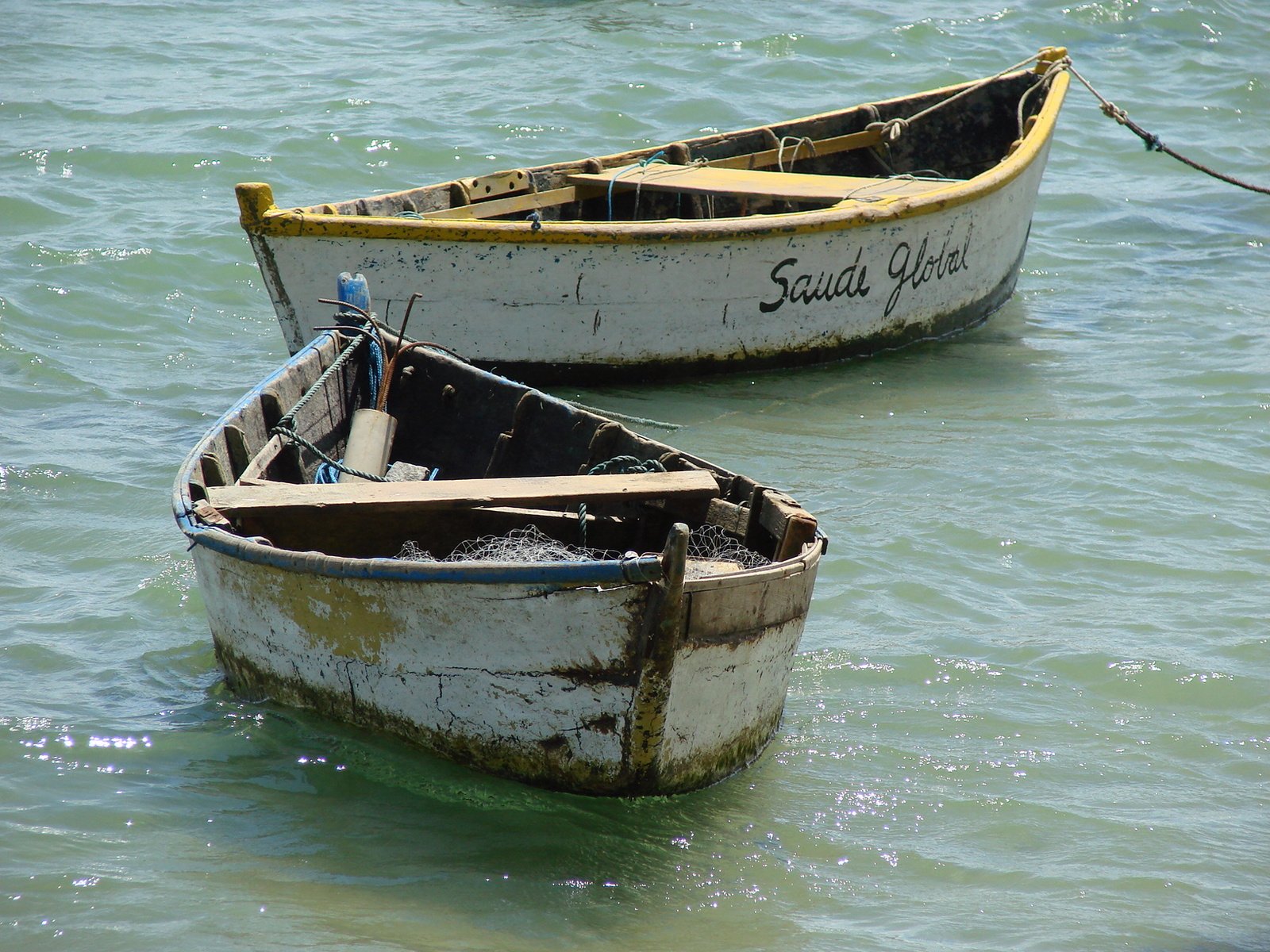 two abandoned row boats floating on top of the water