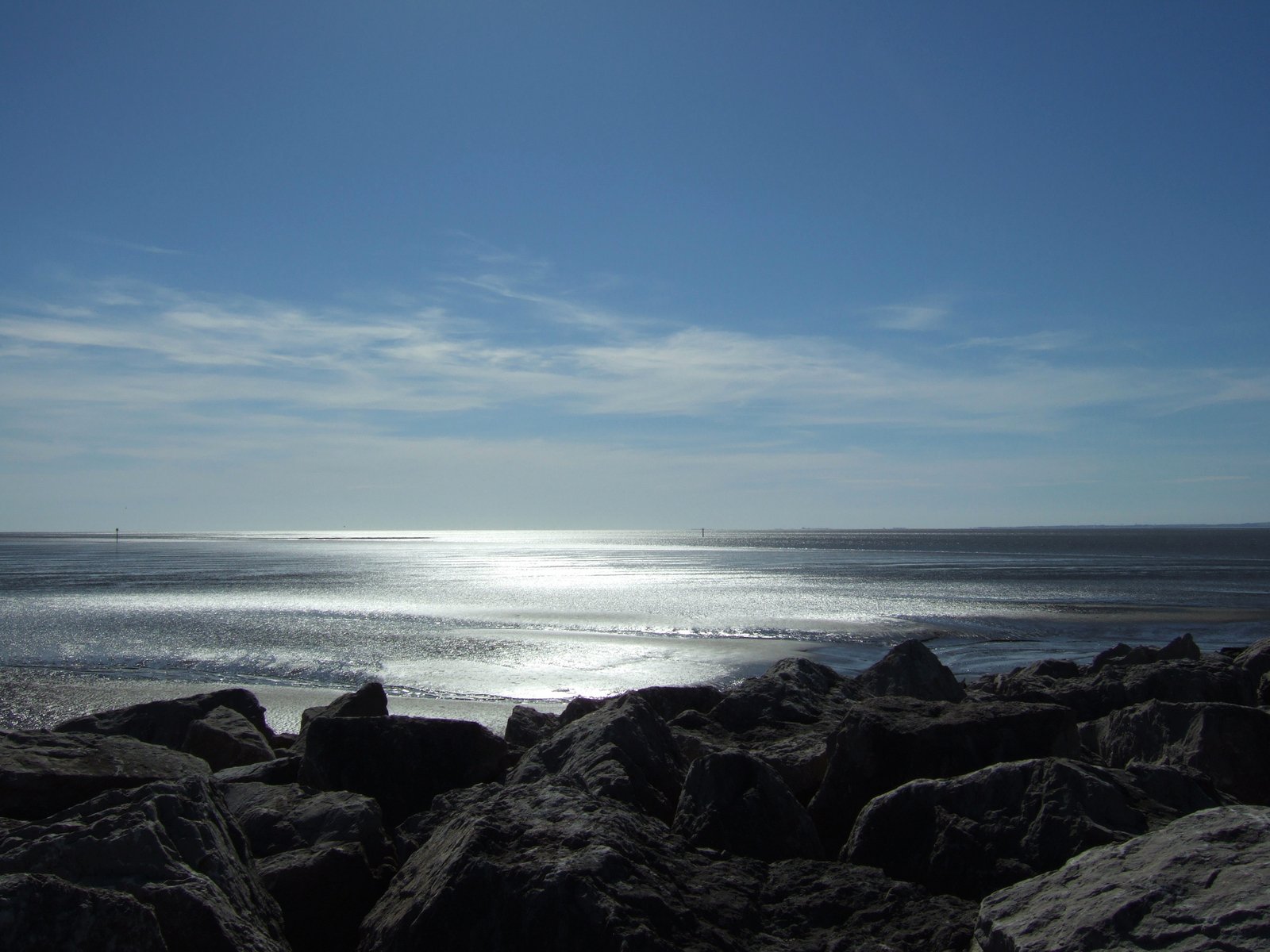 a blue sky is above some water on the beach