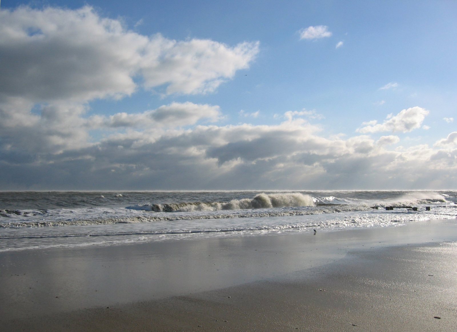 a beach is shown with a few waves and some clouds