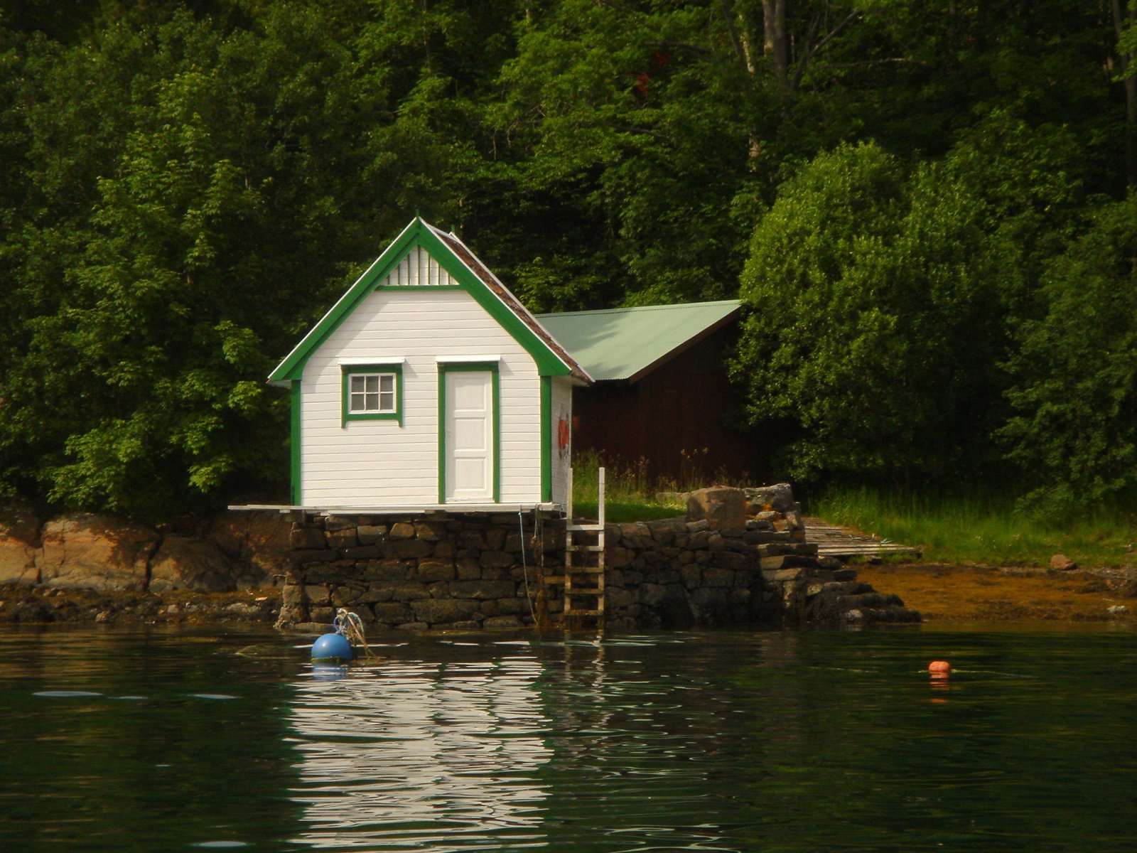 a little boathouse in the water is seen from across the lake