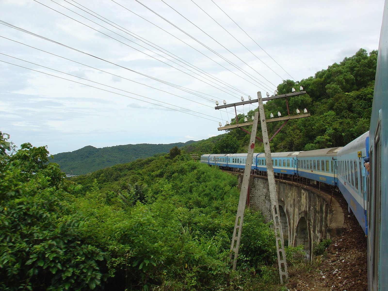 a train driving down a track near a lush green hillside