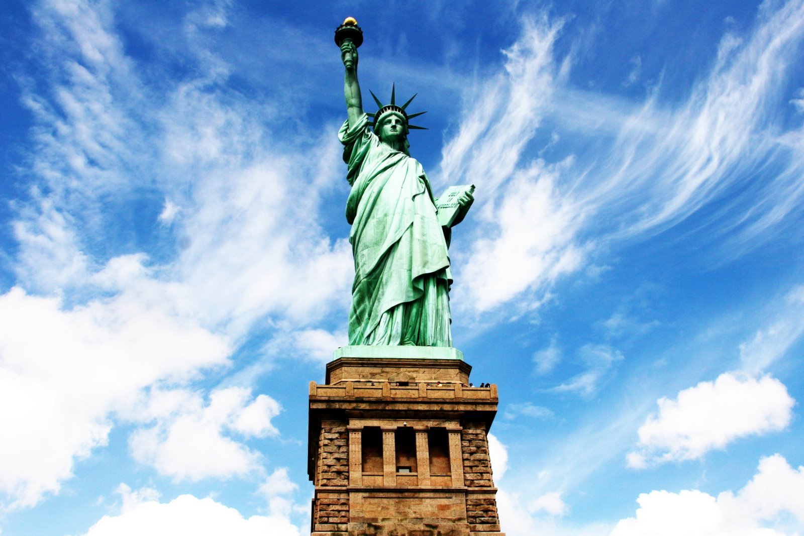 a statue is sitting under the blue sky and clouds