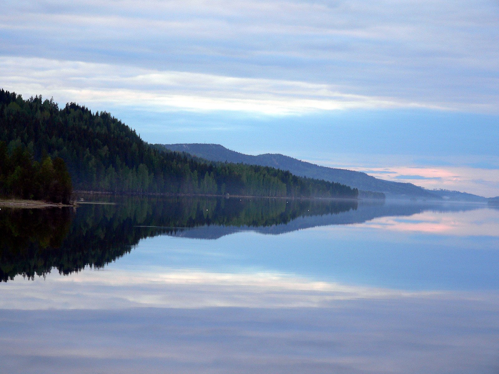 there is a boat out on a still body of water