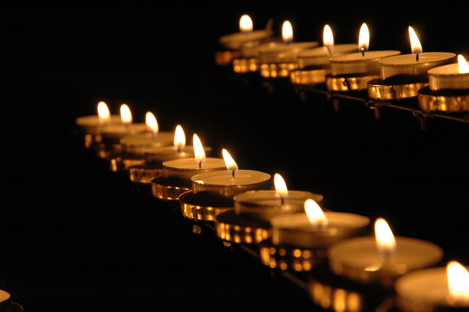 rows of lit candles floating from a mirror in a dark room