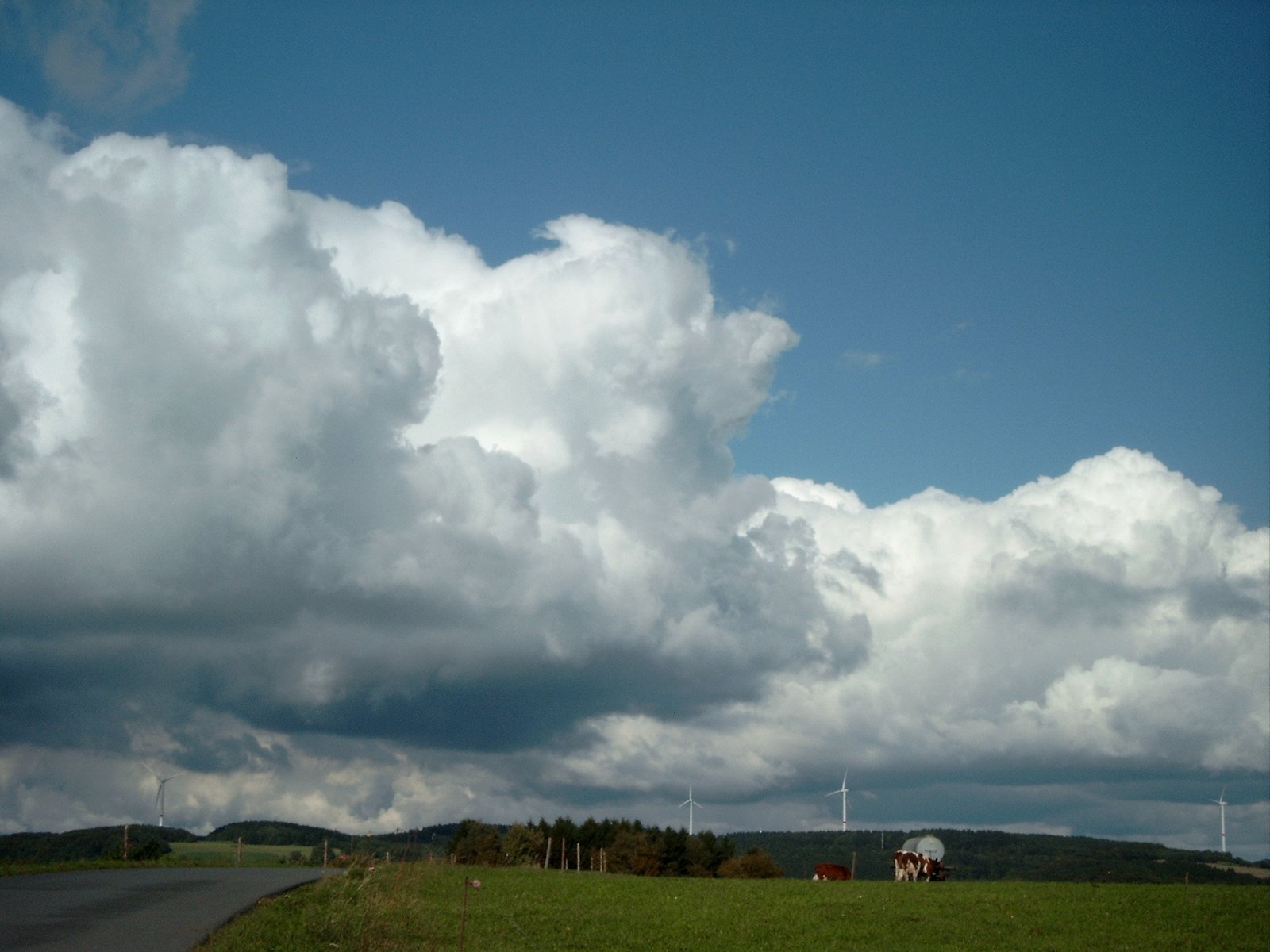 several clouds gather over a large open field