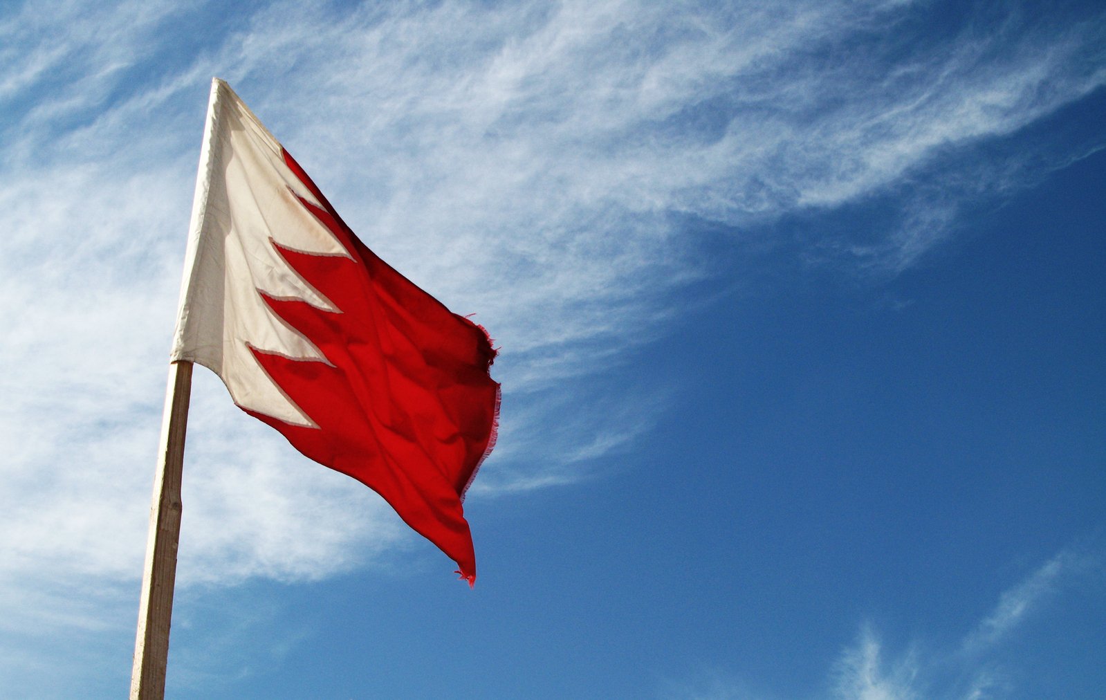 a red and white flag flying high on a clear day