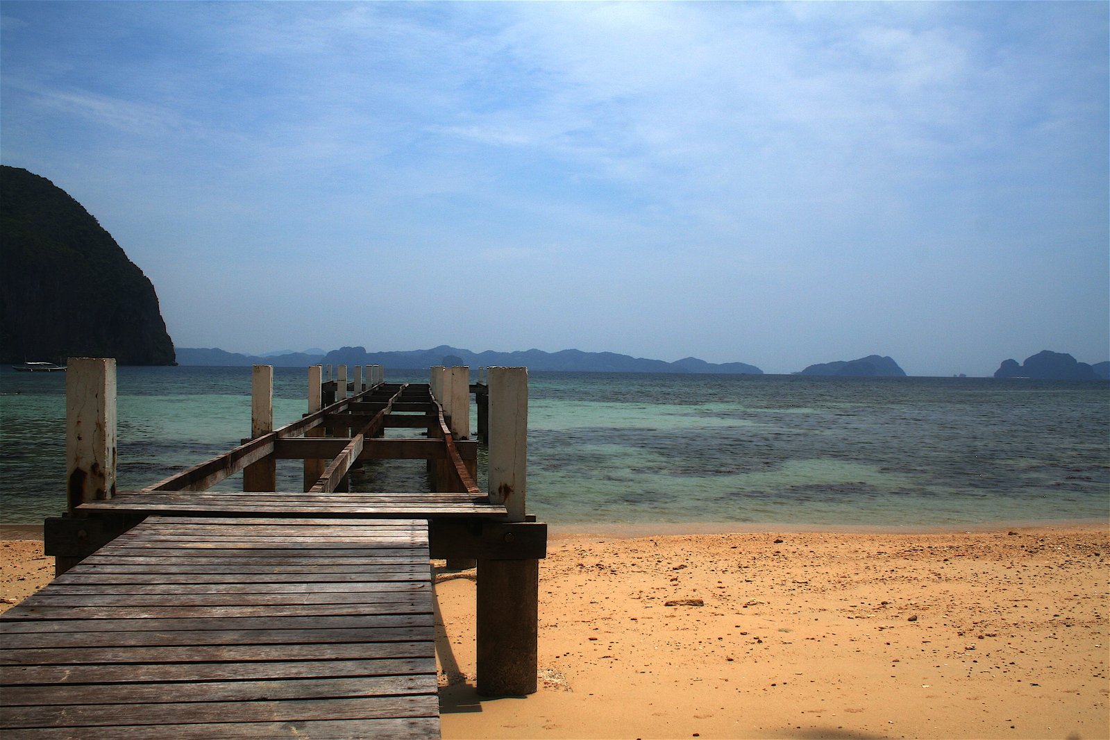 a long wooden pier on the shore of a beach