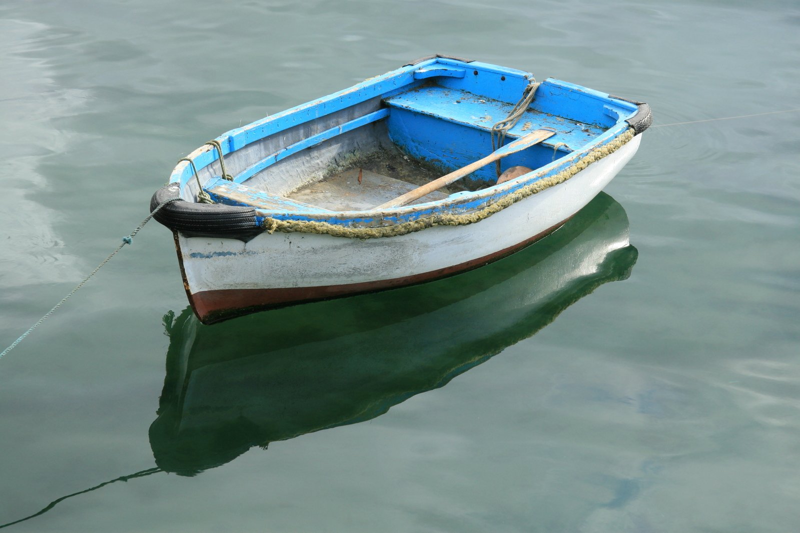 a blue boat tied up on a lake