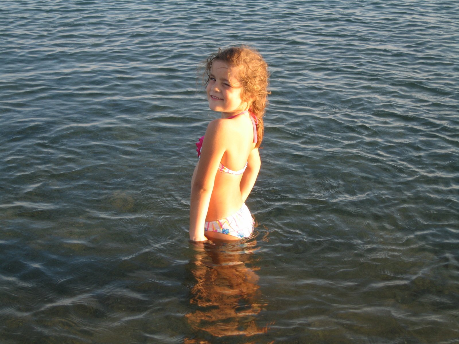 young child standing in water at beach near shore