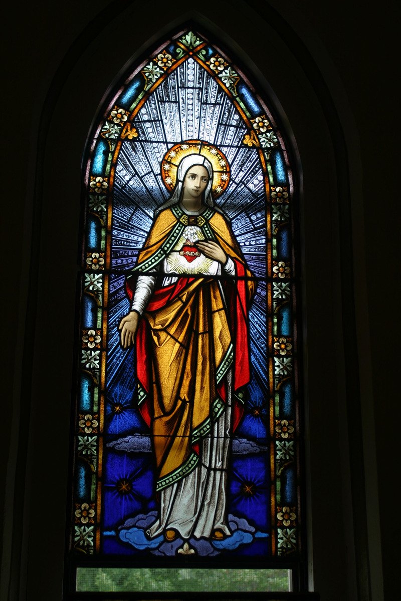 a stained glass window with a statue of jesus holding a child