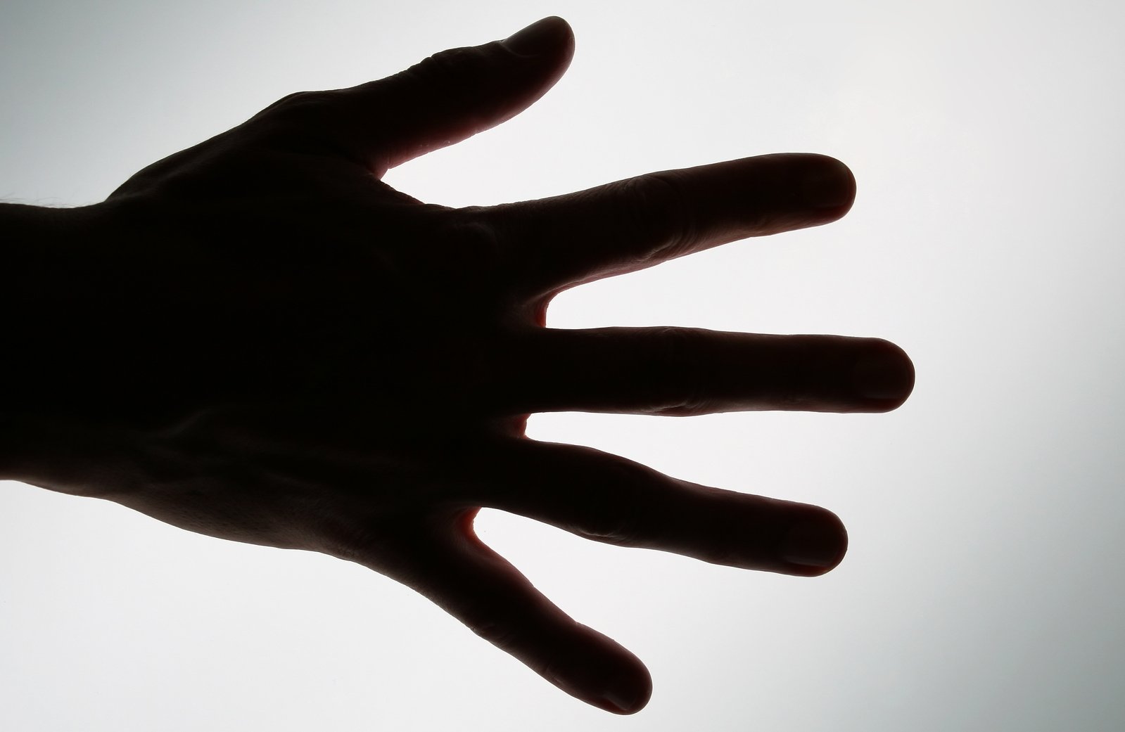 a hand with no fingers is seen silhouetted against the sky