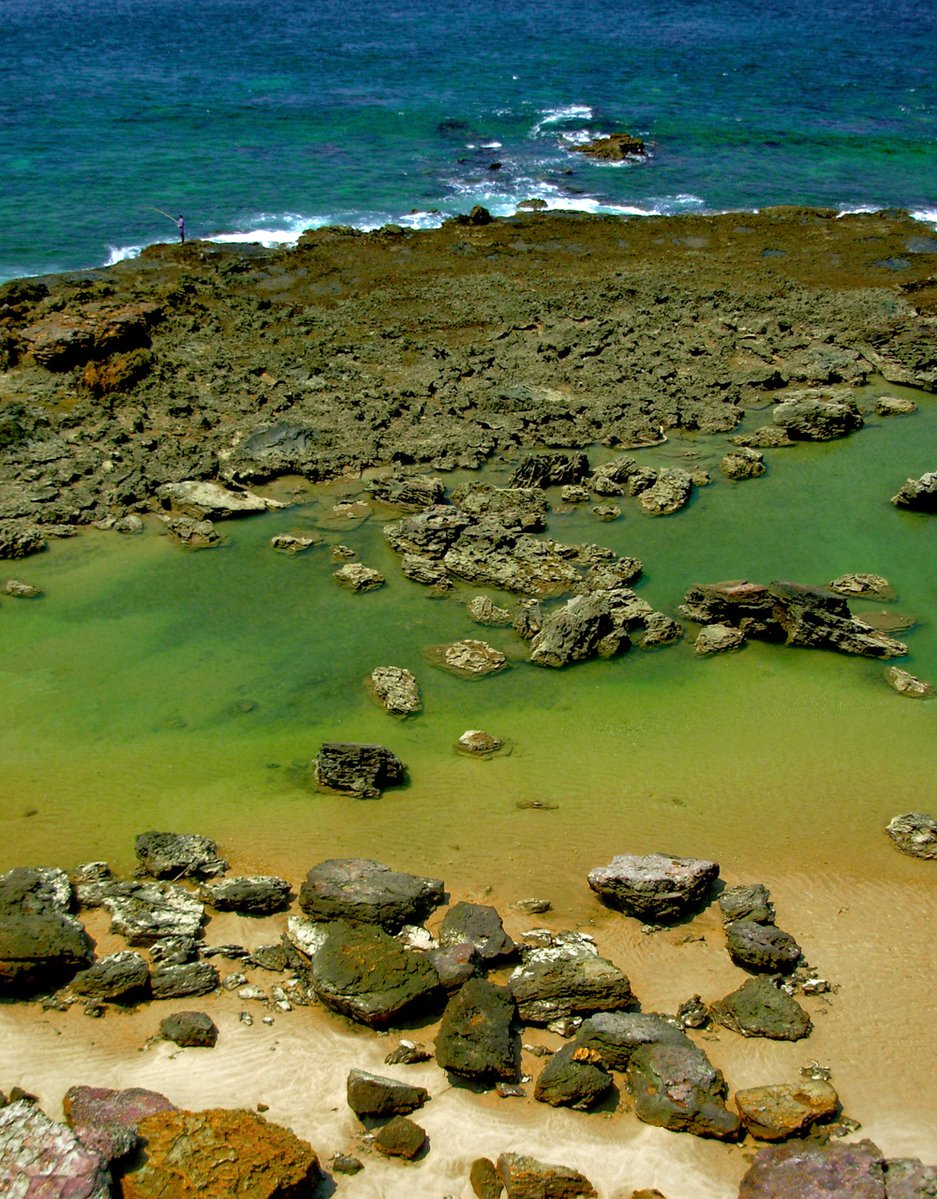 some water rocks and some sand and a hill