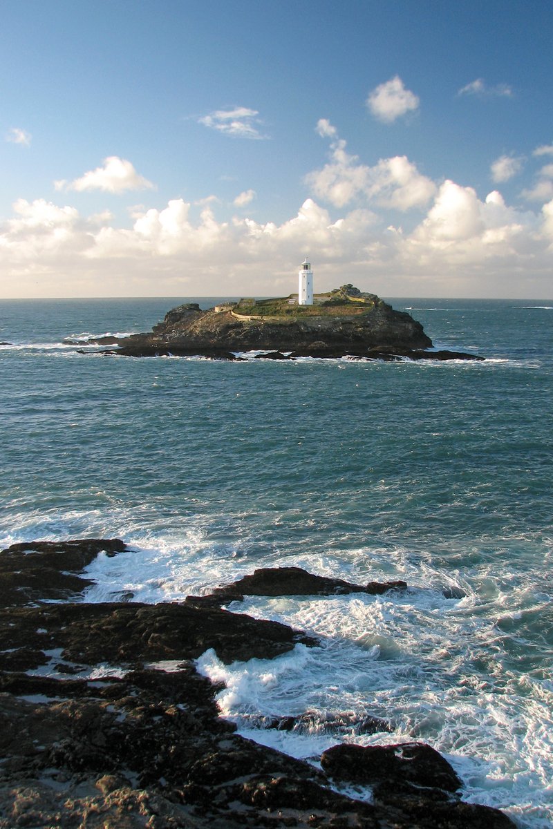 a white light house sitting on top of a small island