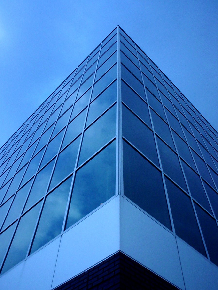 the glass front of an office building against a cloudy sky