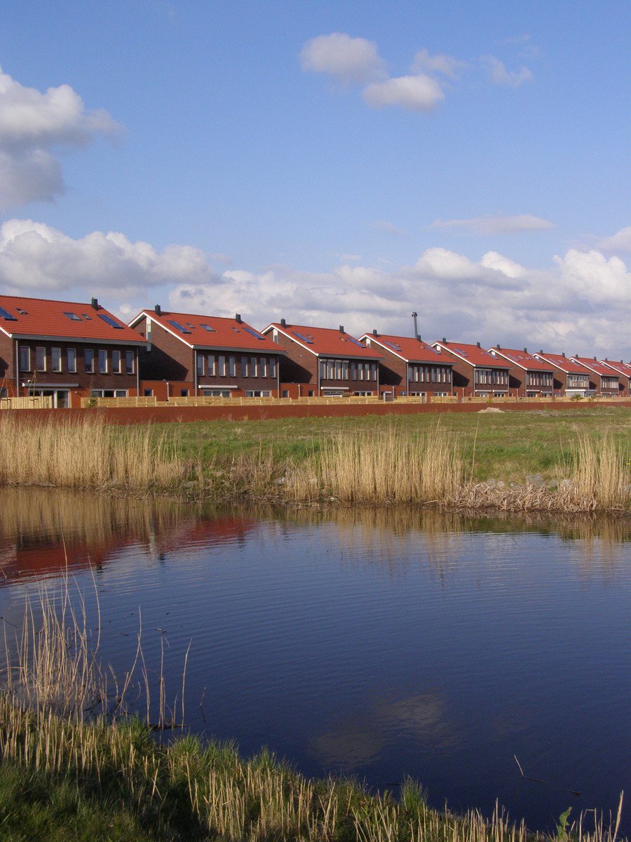 a row of houses sit along side of a body of water