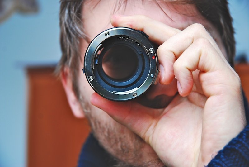 a man with a camera lens is reflected in his lens