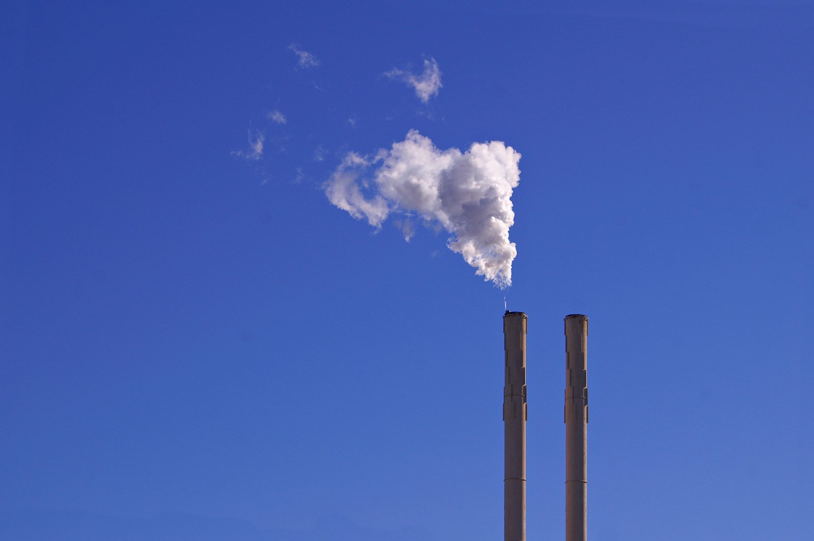 a smoke stack rising up from a building on a sunny day