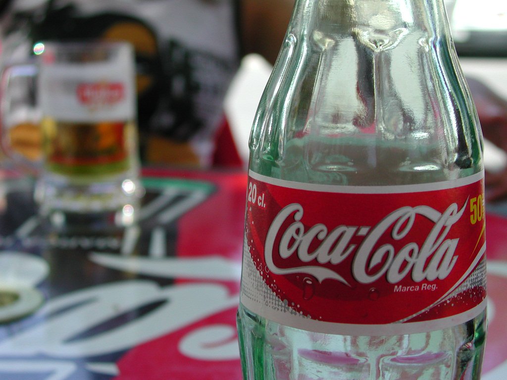 a bottle of coca cola with a green cap sitting on a table