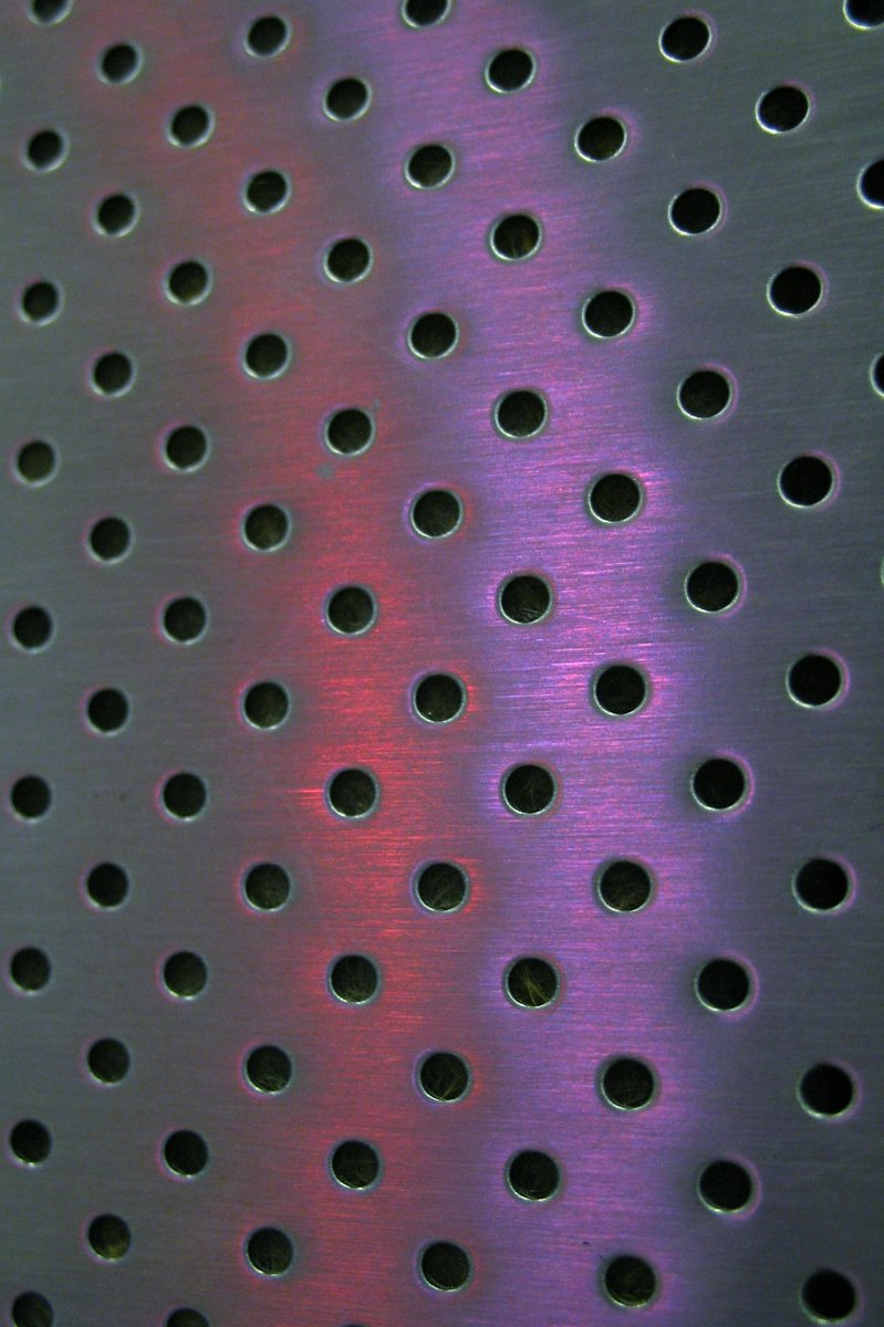 a metal background with holes showing some color