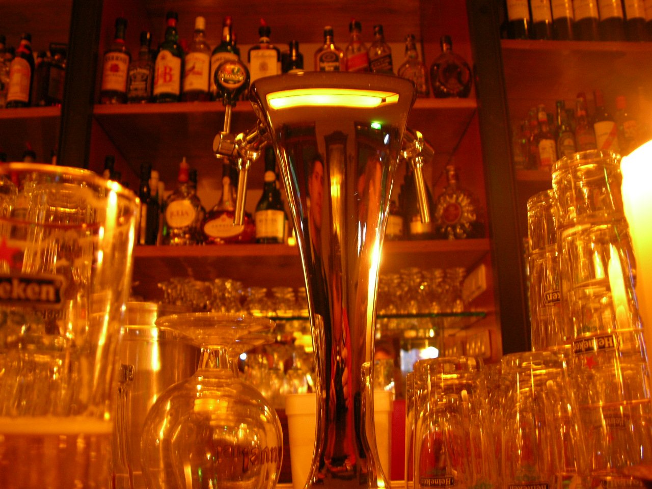 some wine glasses with candles on them next to a shelf full of liquor bottles