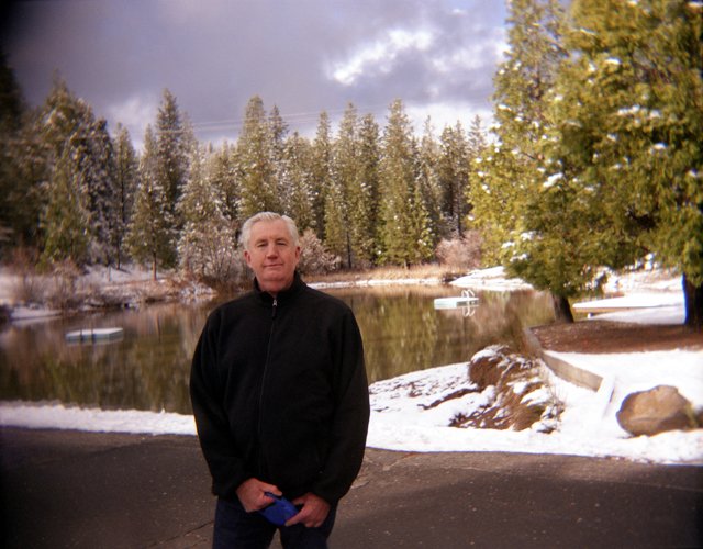 an older man is posing for a po in front of a lake