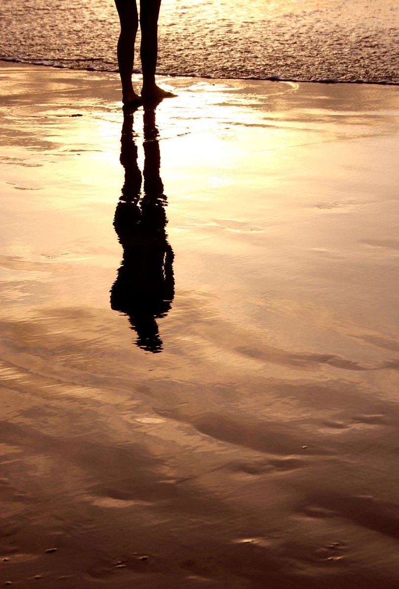 a person walks on the beach at sunset
